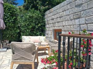a patio with chairs and a table and a stone wall at Villa Casa Belvedere near Dubrovnik in Gruda