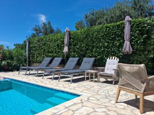 a group of chairs and umbrellas next to a swimming pool at Villa Casa Belvedere near Dubrovnik in Gruda
