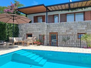 a swimming pool with an umbrella and a house at Villa Casa Belvedere near Dubrovnik in Gruda