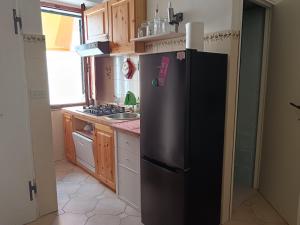 a kitchen with a black refrigerator and wooden cabinets at Casa Cavour 15 in Porto Santo Stefano