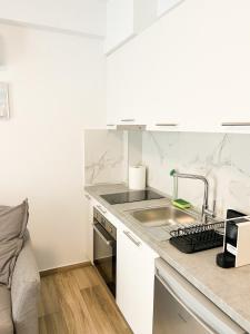 a white kitchen with a sink and a counter at Sea Shell Apartment - Paralia Ofriniou, Swimming pool, Starlink WIFI in Orfánion