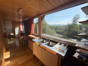 a kitchen with a sink and a large window at La Cheminée - Chambres Gîtes Appartements et Mobile Homes avec Bar-Restaurant in Tardets-Sorholus