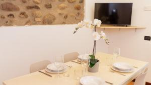 a dining room table with white plates and a vase of flowers at Gomes Comfort House Borghetto in Valeggio sul Mincio