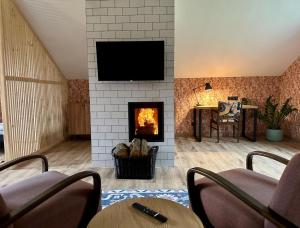 a living room with a fireplace with a tv on a wall at Dom pod Niebem in Lucimia