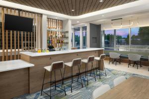 a lobby with a bar with stools and a tv at SpringHill Suites by Marriott Atlanta Covington in Covington