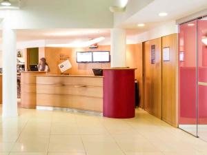 a woman sitting at a counter in a hospital lobby at Hotel ibis Setubal in Setúbal
