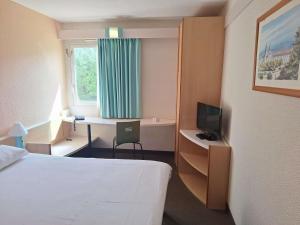 a hotel room with a bed and a desk with a television at Hotel ibis Setubal in Setúbal