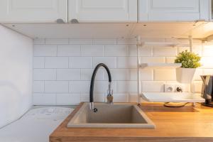 a kitchen sink in a kitchen with white tiles at Lublin Old Town Studio by BookingHost in Lublin +16 photos