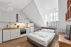 a white bedroom with a bed and a kitchen at Lublin Old Town Studio by BookingHost in Lublin