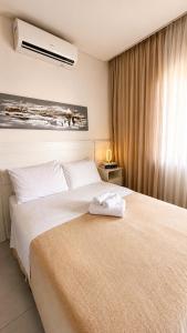 a bedroom with a large white bed and a window at MaxLoft - Studio Moderno in Joinville