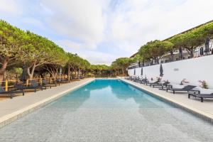 a pool at a resort with chairs and trees at Octant Praia Verde in Praia Verde