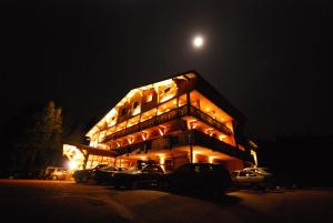 un bâtiment avec des voitures garées dans un parking la nuit dans l'établissement Chalet Hotel Le Collet, à Xonrupt-Longemer