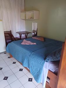 a bedroom with a blue bed and a table at Pousada e Restaurante Chateau Soneka in Algodoal