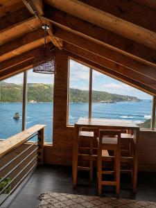 a dining room with a table and a view of the ocean at Cabaña Mirador de ballenas,Chiloé in Ancud