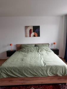 a bed with a green comforter in a bedroom at Mocafe Schloßbleiche in Wuppertal