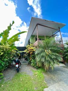 a house with a motorcycle parked in front of it at Heliconia Suite 5min to Waterfall - Shared Pool Pool in Fortuna