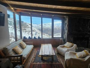 a living room with a couch and a table in front of a window at Cordillera Hostel in Farellones