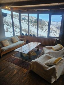 a room with a table and couches in a room with snow at Cordillera Hostel in Farellones