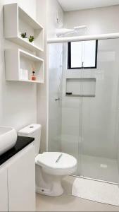 a white bathroom with a toilet and a shower at MaxLoft - Studio Moderno in Joinville +9 photos