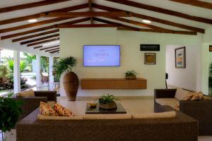 a living room with couches and a television on a wall at Villa de lujo a 20 mins Buga con Piscina privada, Jacuzzi y BBQ in Guacarí