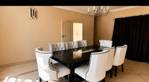 a dining room with a black table and white chairs at The Vine House in Harare +3 photos