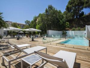 a swimming pool with lounge chairs and a table and a pool at Mercure Ajaccio in Ajaccio