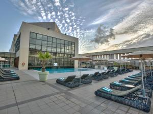 a pool with lounge chairs and umbrellas in front of a building at Sofitel Algiers Hamma Garden in Alger
