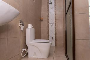 a bathroom with a toilet and a shower at Auregi Villas in Diani Beach +11 photos