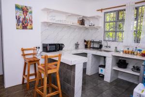 a white kitchen with two chairs and a counter at Auregi Villas in Diani Beach