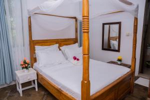 a bedroom with a four poster bed with a mirror at Auregi Villas in Diani Beach
