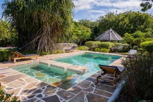 a swimming pool with a bench and a table and chairs at Auregi Villas in Diani Beach