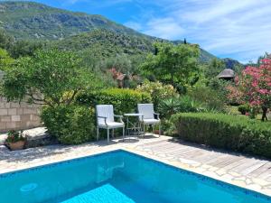 a pool with two chairs and a table with a mountain in the background at Villa Casa Belvedere near Dubrovnik in Gruda +64 photos