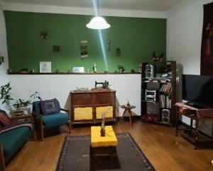 a living room with a green wall with a beam at Wind & Way Hostel in Valparaíso