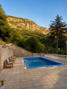 a swimming pool with two chairs and a hill at Vila Băncii 1888 by SunGarden in Băile Herculane