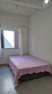 a bedroom with a pink bed with a window at Casa Real in Guarapari