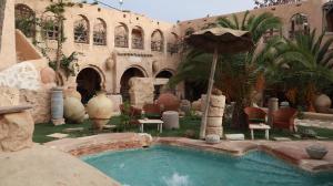 a swimming pool with an umbrella in a courtyard at Tenasbook Jnen Rayhane in Midoun