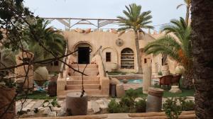 a house with a swimming pool and palm trees at Tenasbook Jnen Rayhane in Midoun