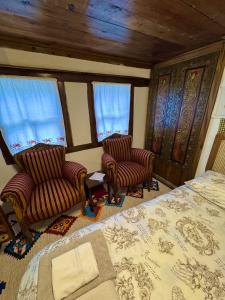 a bedroom with two chairs and a bed and windows at Geyikli Konak in Mudurnu