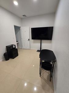 a room with a table and a television and a stool at Miami Stay - Pool, Parking, & Affordable Transportation in Tamiami