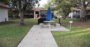 a table with a blue umbrella and a bench at Serene Florida Oasis in Inverness +2 photos