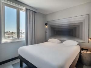 a bedroom with a large white bed and two windows at ibis Saint Quentin Centre Basilique in Saint-Quentin