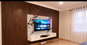 a living room with a flat screen tv on a wall at The Vine House in Harare