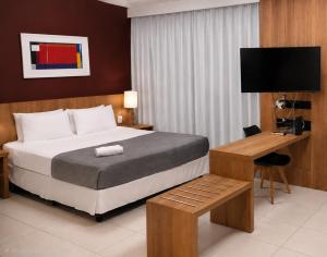 a bedroom with a bed and a desk with a television at Flat & Suite Premium - Rio Centro - Barra - Farmasi Arena in Rio de Janeiro