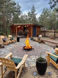 a fire pit in a yard with chairs and a cabin at BORSKÓWKA domki z balią z jacuzzi i sauna in Borsk