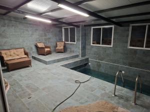 a room with a swimming pool with two chairs at Los corzos in Burgohondo