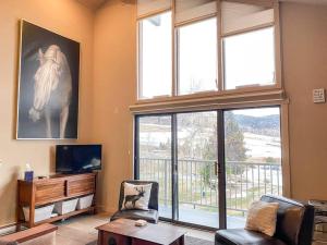 a living room with a large window with a horse picture at Slopeside Chalet in Steamboat Springs