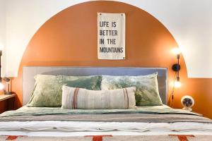 a bed with an orange wall with a sign above it at Sunset Sanctuary in Steamboat Springs