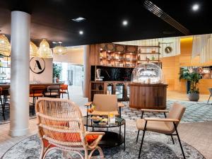a restaurant with chairs and tables and a bar at Novotel Belfort Centre Atria in Belfort