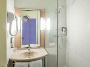 a bathroom with a sink and a shower with a mirror at ibis Saint Brieuc Yffiniac in Yffiniac