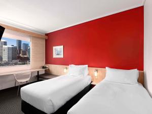 two beds in a hotel room with a red wall at ibis Sydney Darling Harbour in Sydney +59 photos